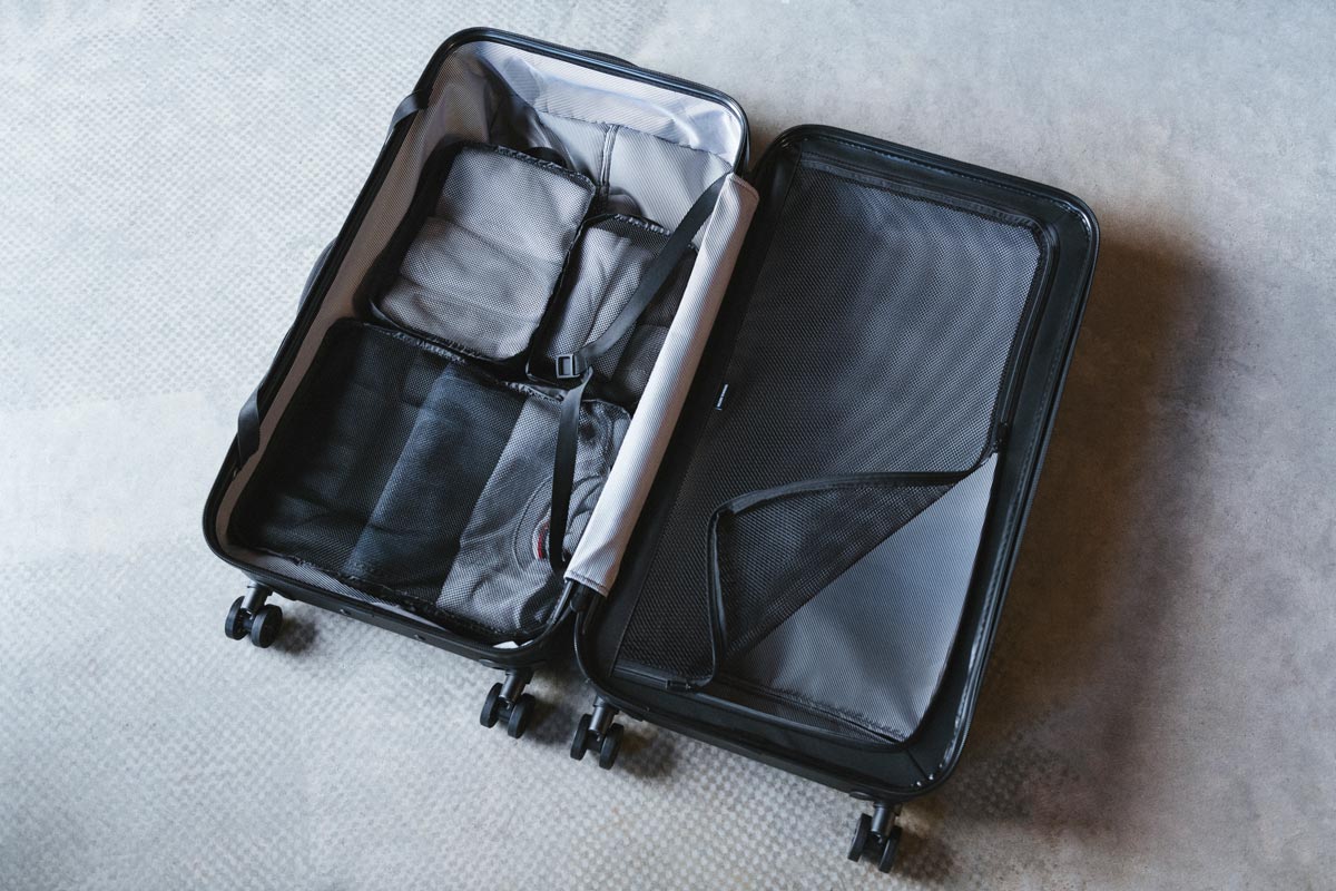 A Herschel Trade Luggage Large suitcase unzipped and lying open on the ground showing the internal dividers